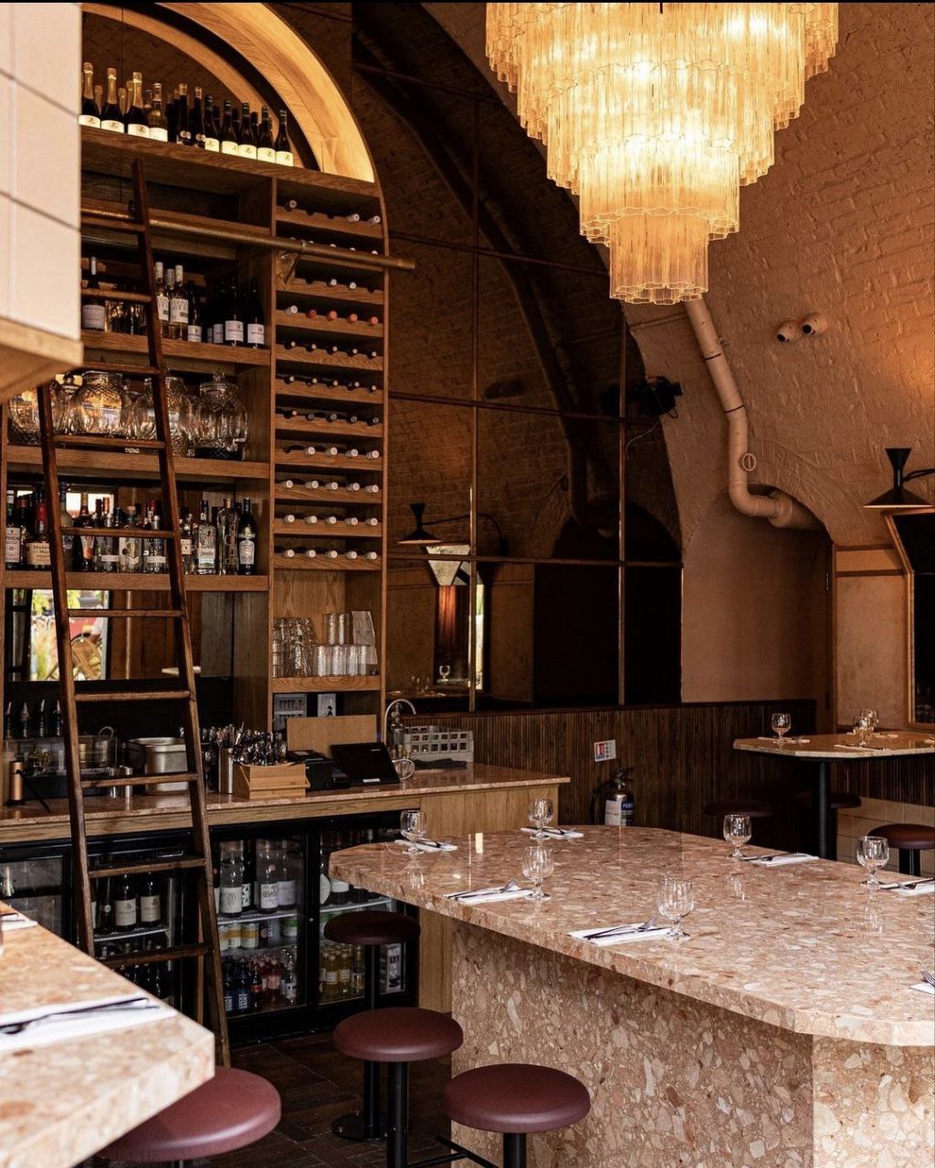 Finished restaurant bar with terrazzo counter, arched wine shelving and chandelier