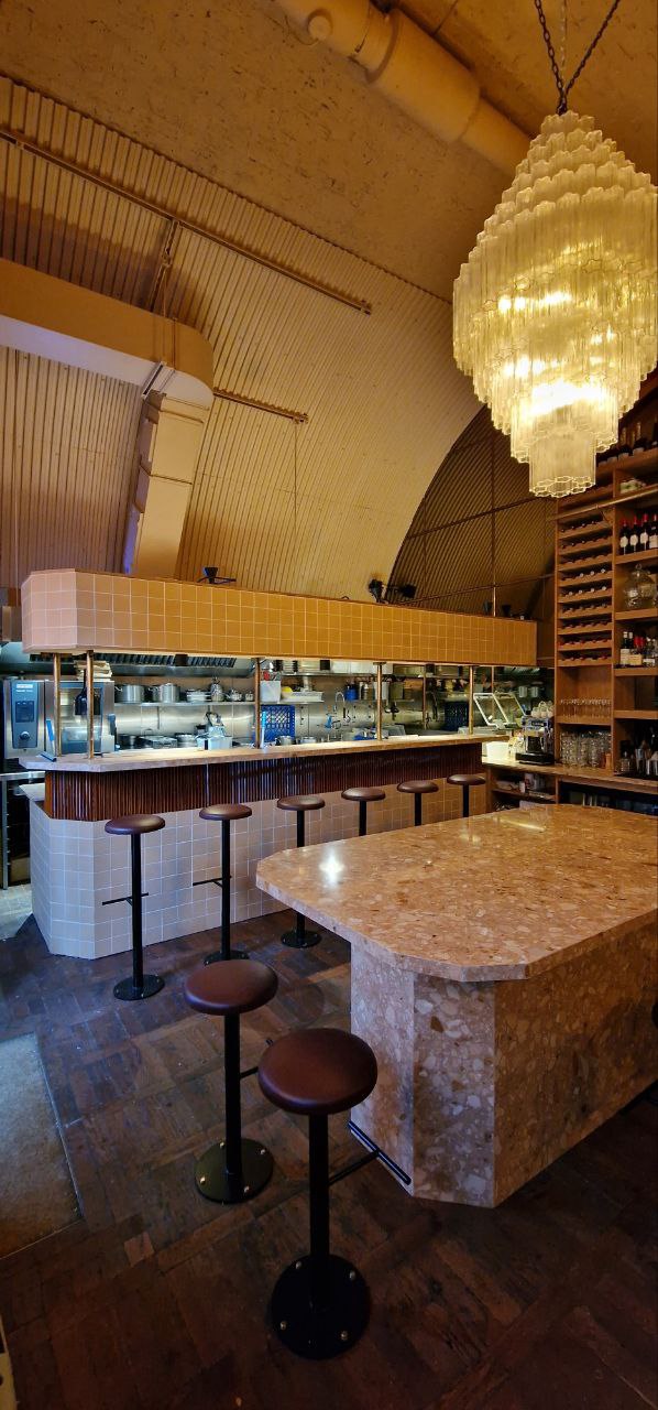 Finished restaurant wider angle showing arched ceiling, chandelier and full bar