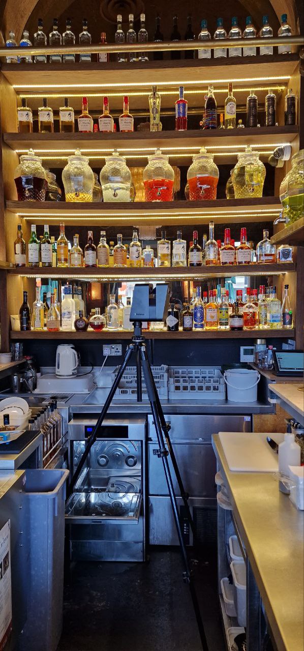 LiDAR scanner scanning behind a bar, capturing bottle shelves